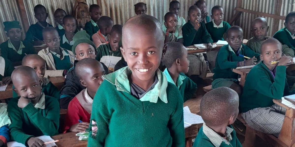 Smiling student in green school uniform inside a classroom.