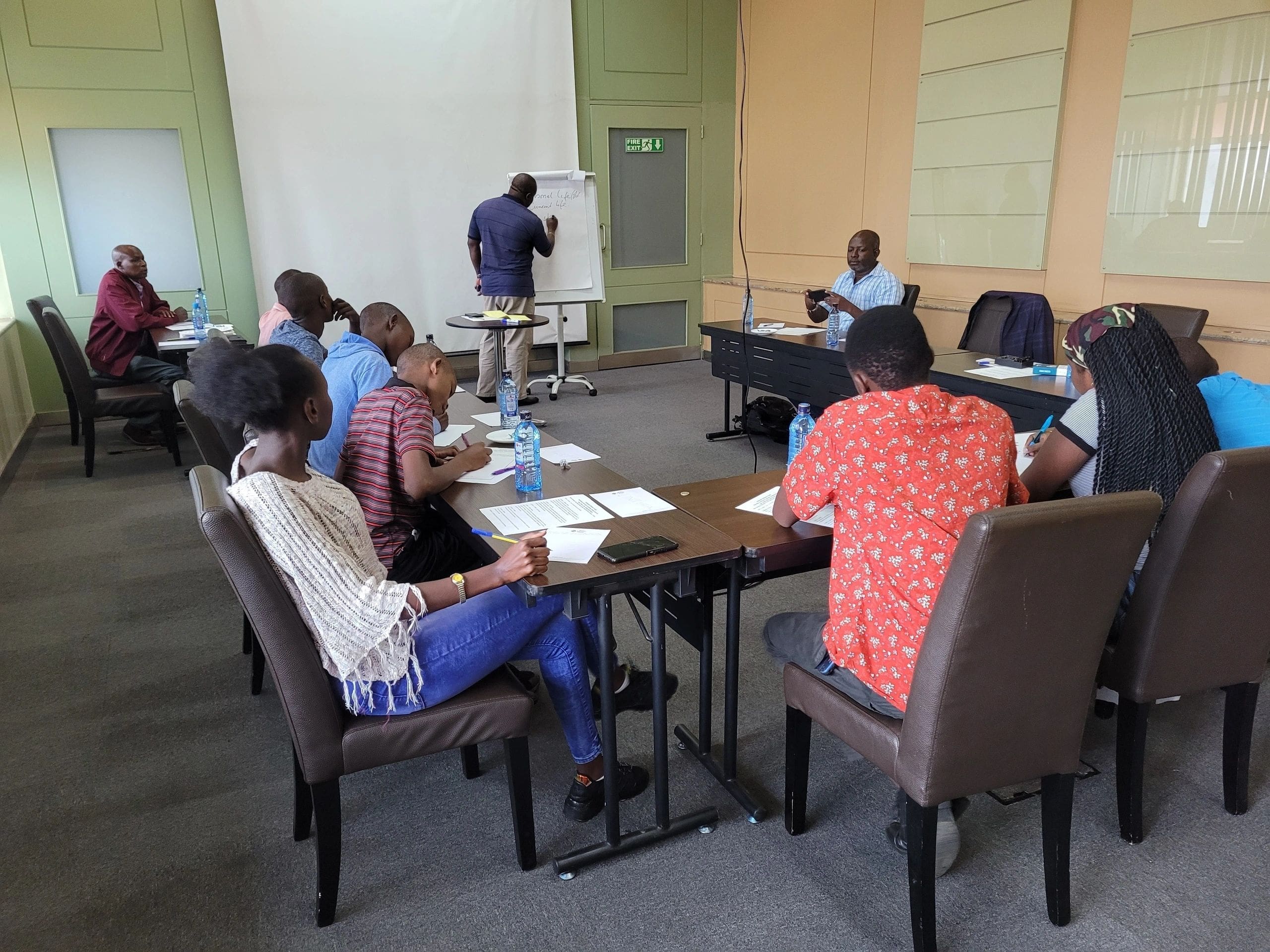People attending a meeting in a conference room with a presenter at the front.
