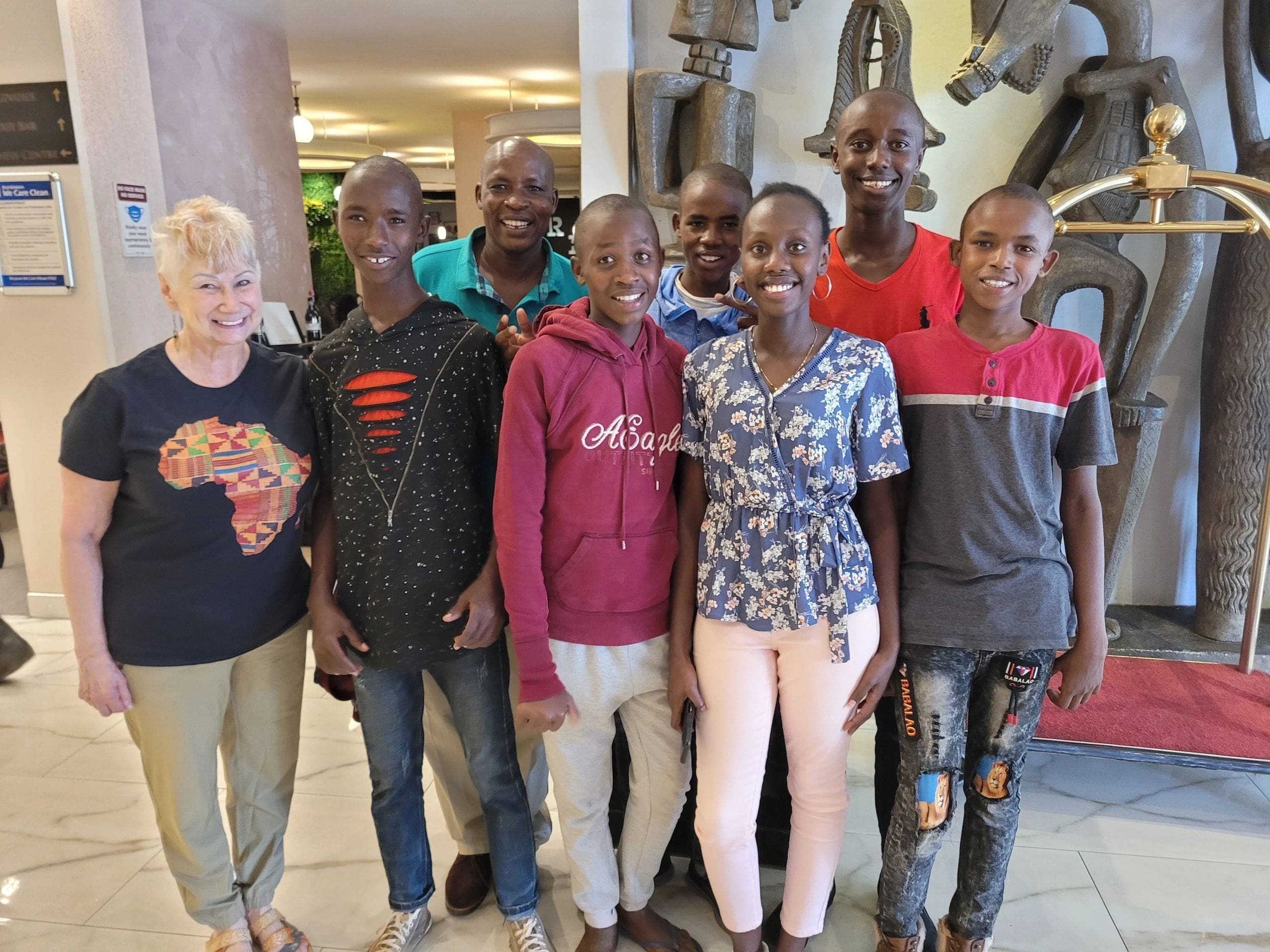 A group of seven boys standing together indoors, smiling for a photo.