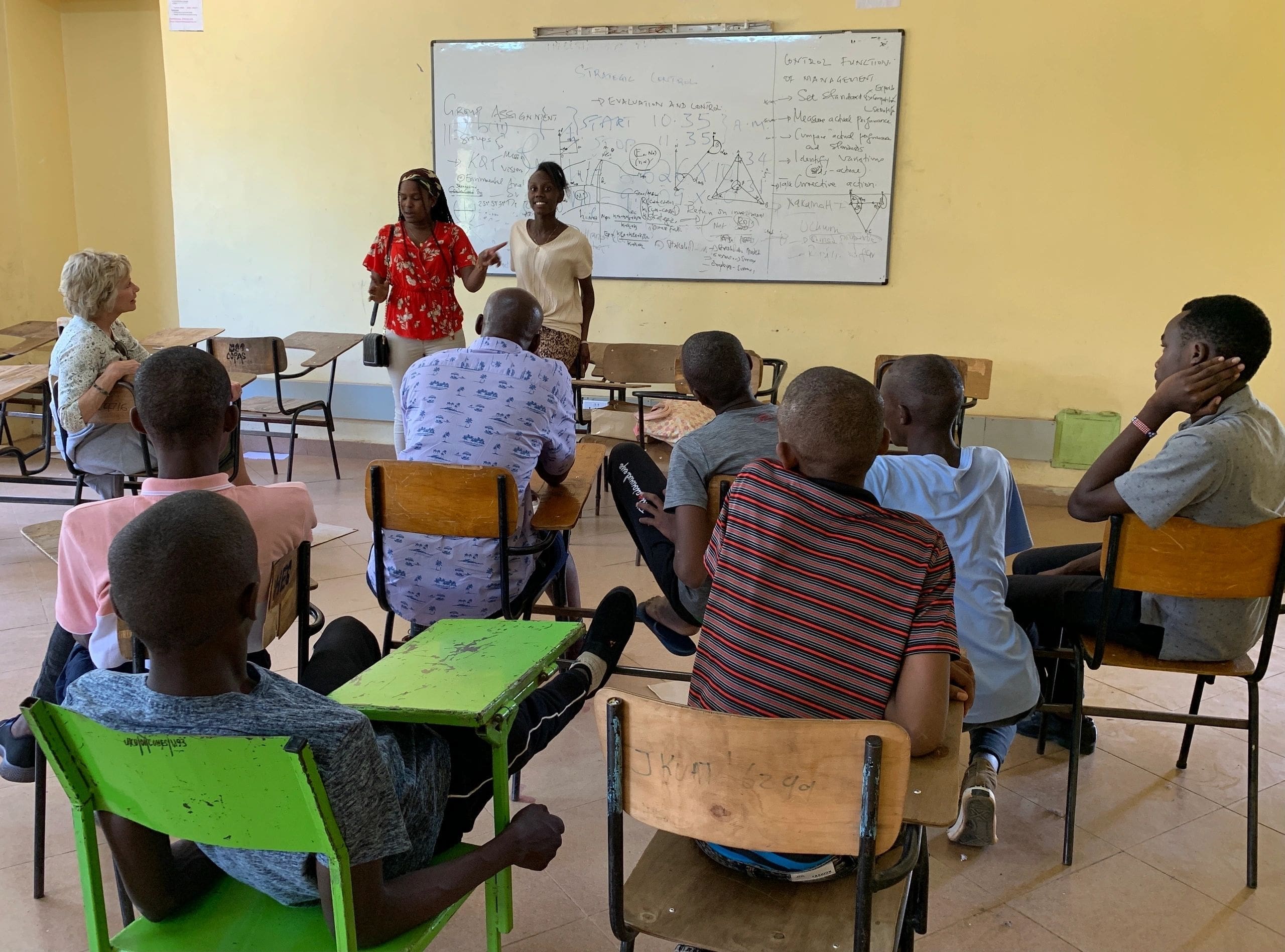 Students attentively listen to a teacher explaining a lesson on the board in a classroom.