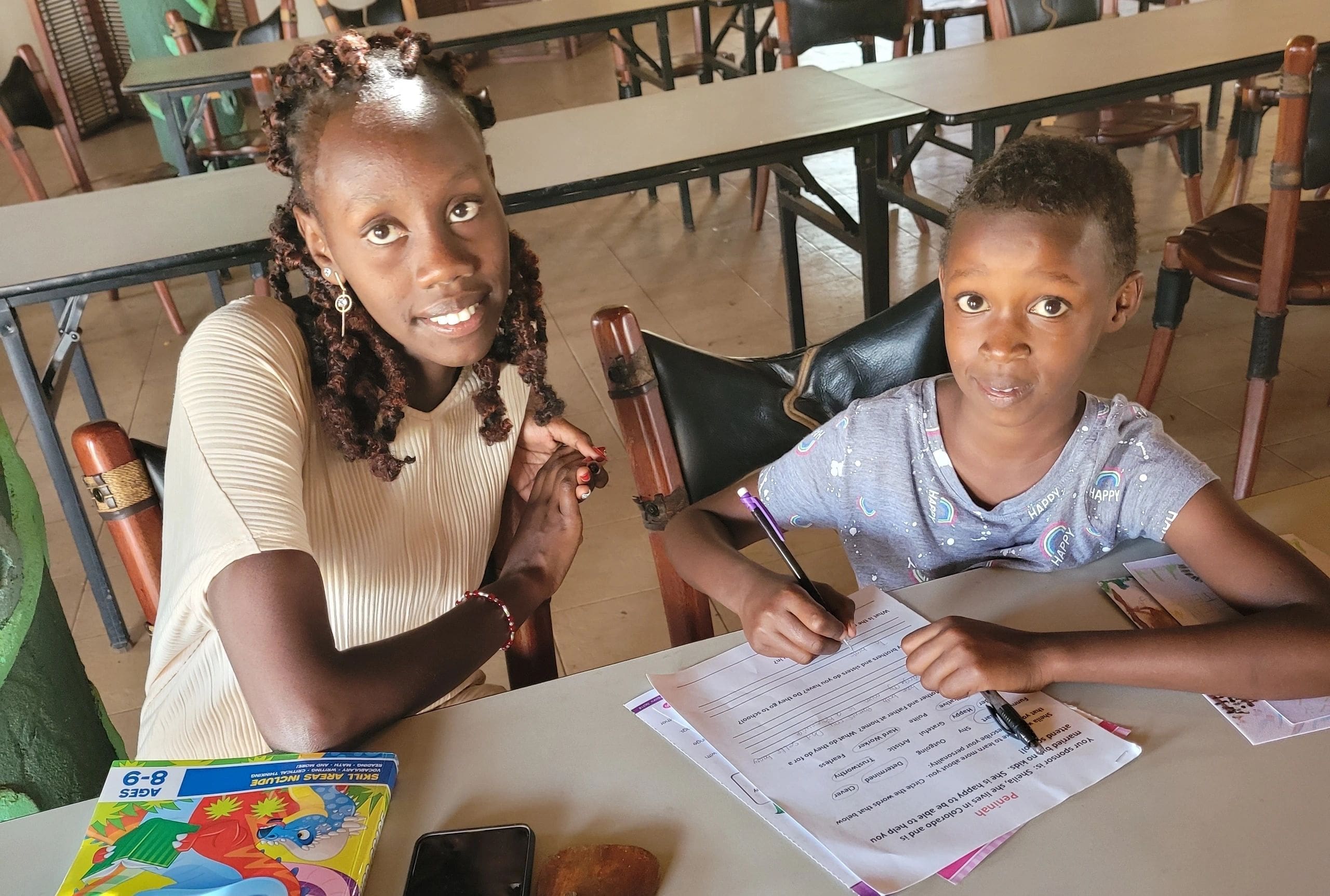 Two children studying together at a table in a classroom.