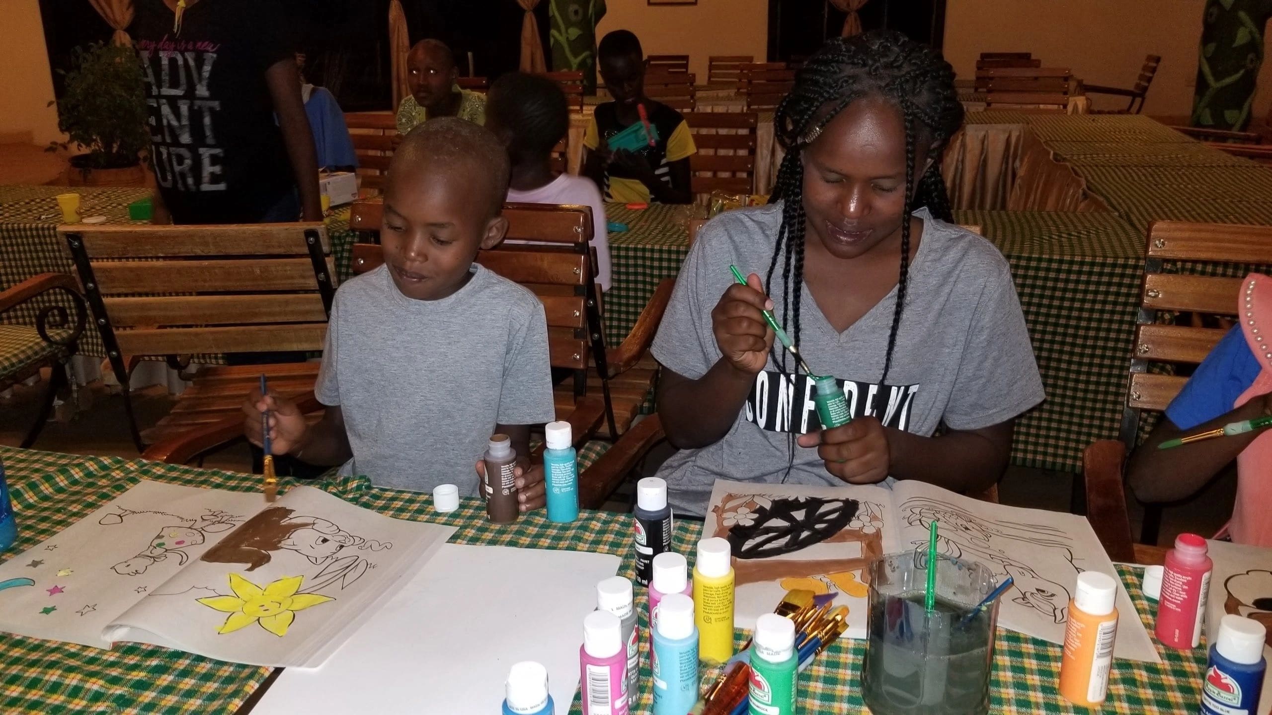 Two children painting and crafting at a table filled with art supplies.