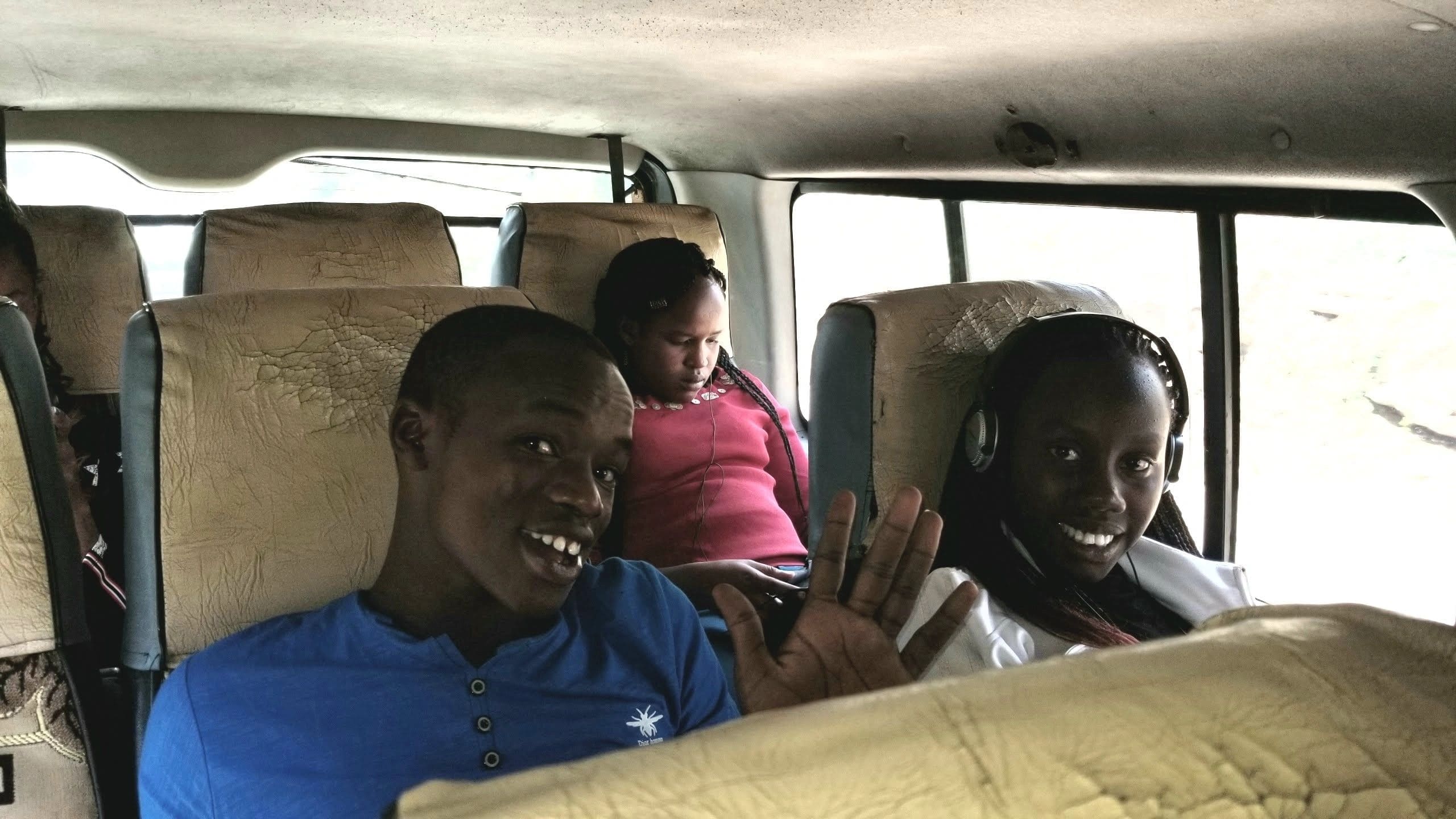 Three people sitting inside a vehicle, smiling and relaxed.
