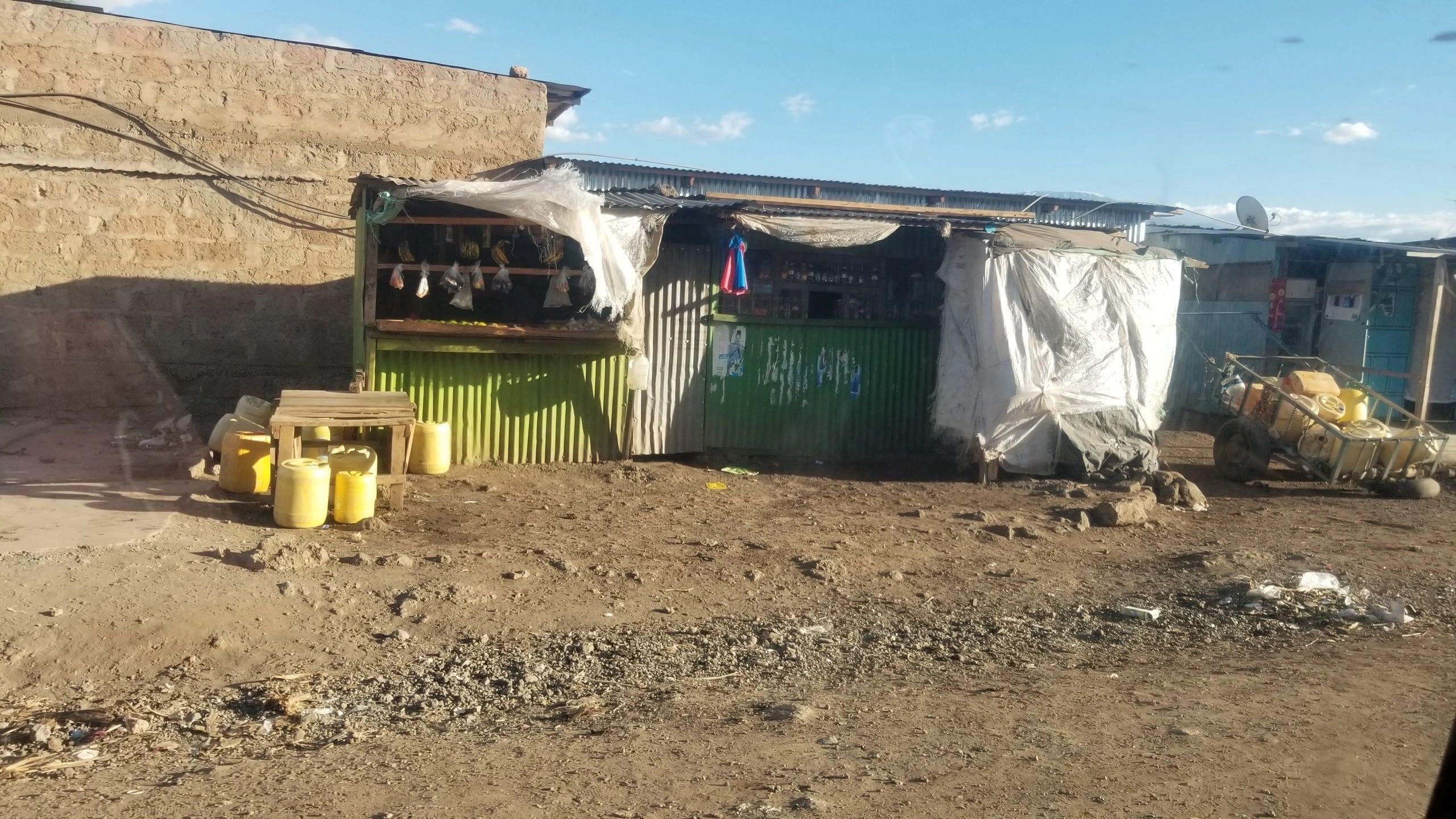 A small, rustic outdoor market stall with produce under a tarp.