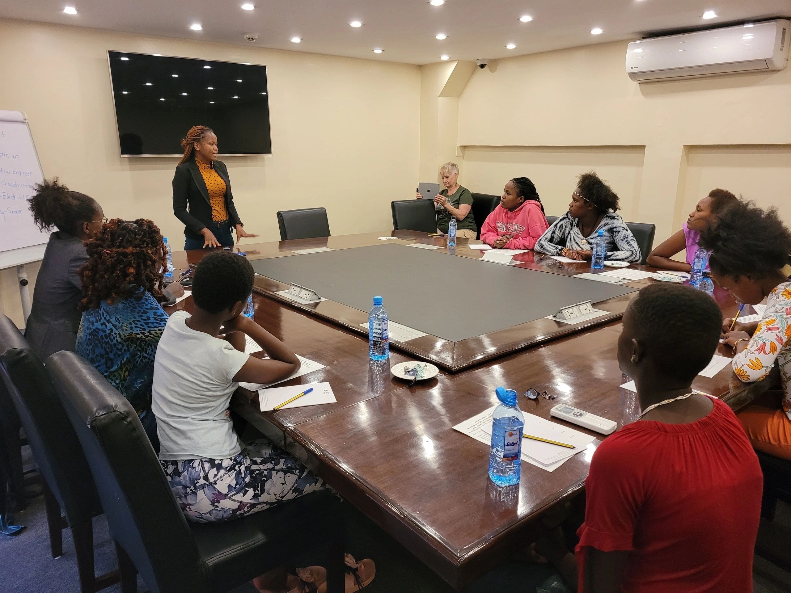 A group meeting in a conference room with a speaker addressing attendees.