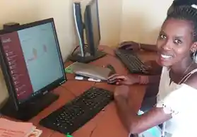 A young person smiling while using a computer.