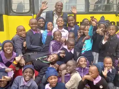 A joyful group of children and adults posing together outdoors.