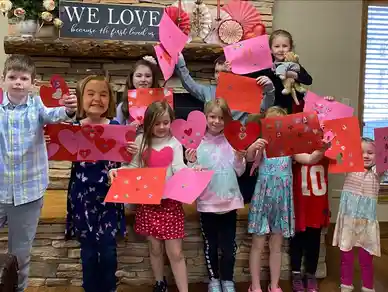 Group of kids holding colorful heart-shaped cards, smiling joyfully.