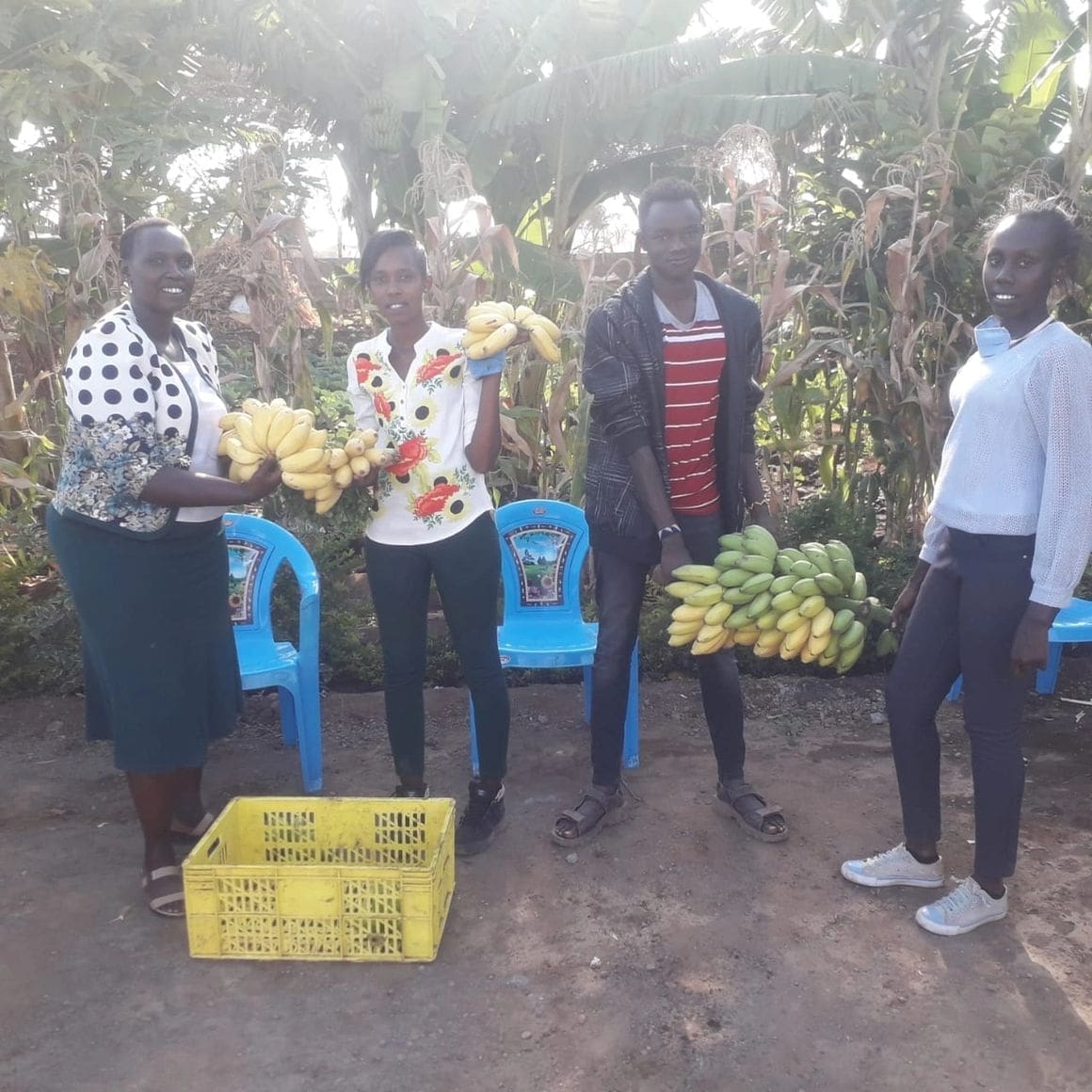 Four men standing outdoors with crates of bananas and flowers.