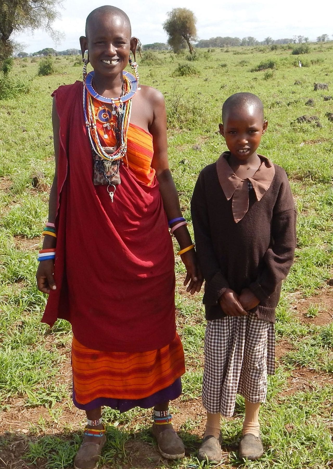 Two people standing outdoors in traditional clothing.
