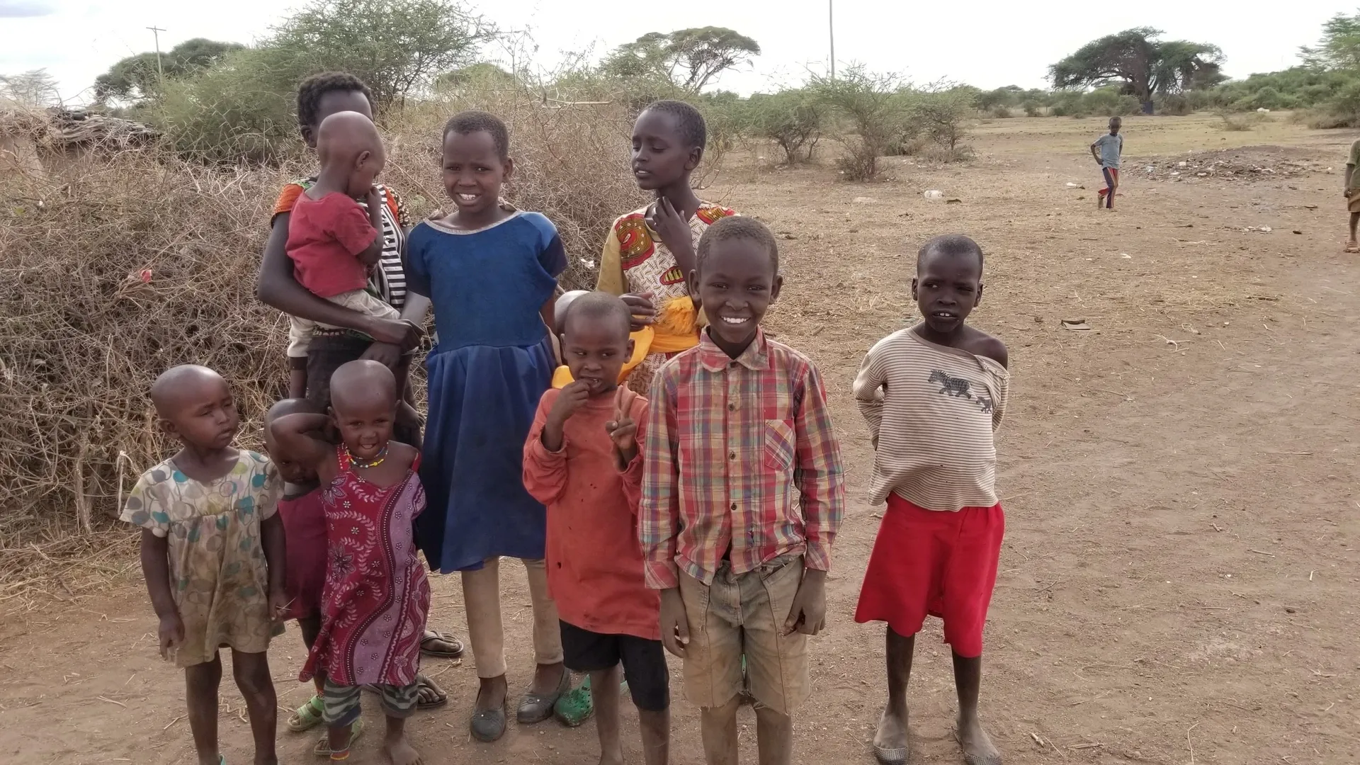A group of children standing outdoors in a rural area.