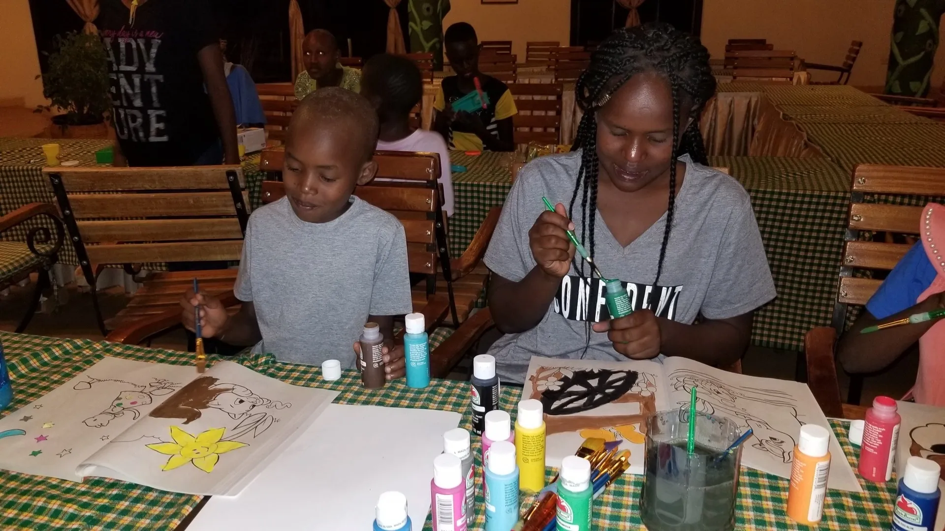 Two children painting and crafting at a table with art supplies.