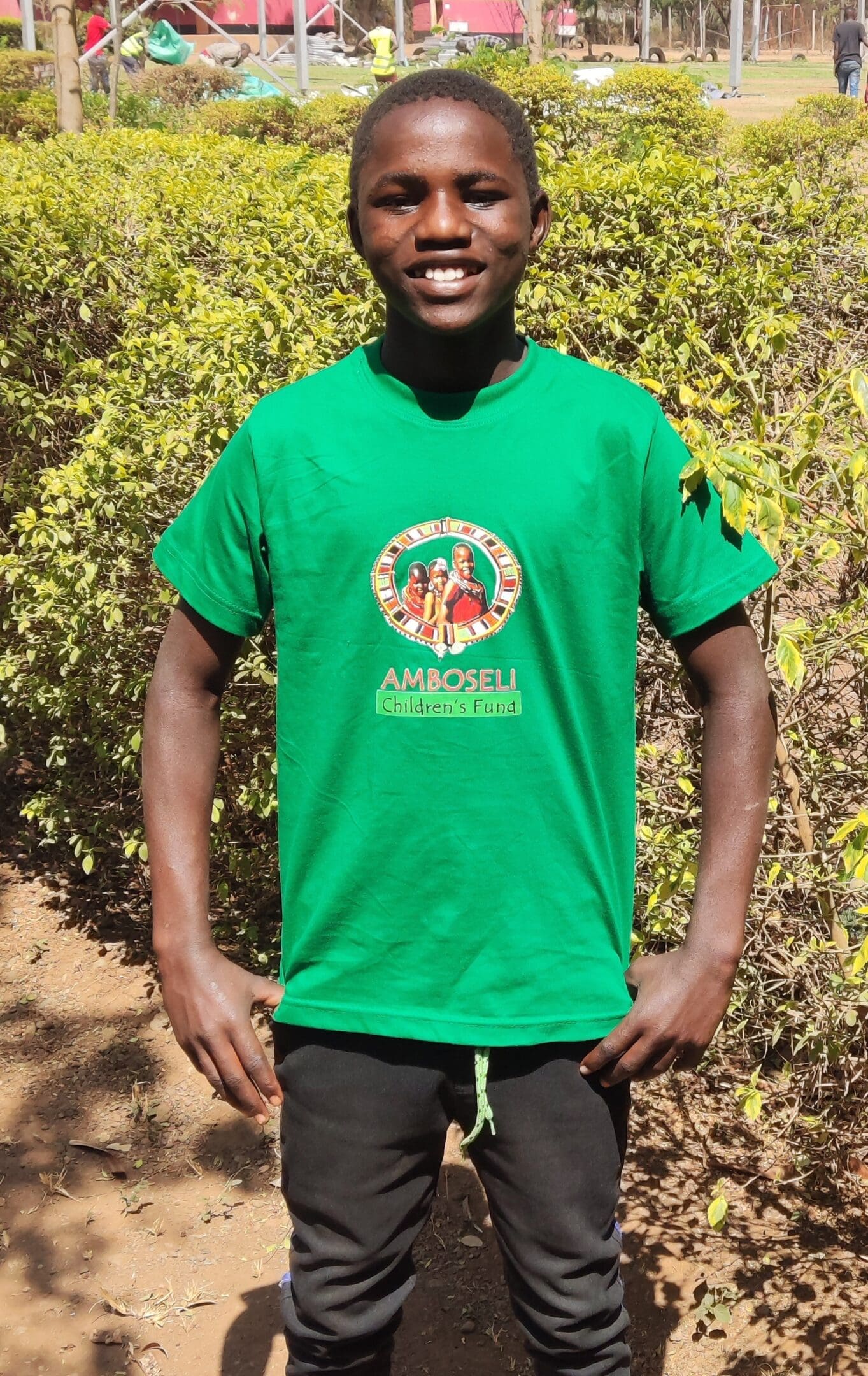 Smiling man wearing a green t-shirt outdoors with trees in the background.