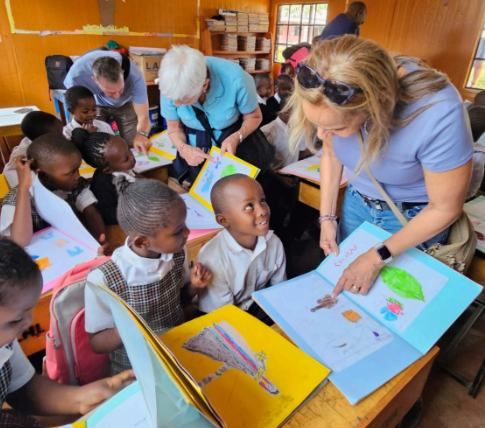 Adults and children sharing drawings in classroom